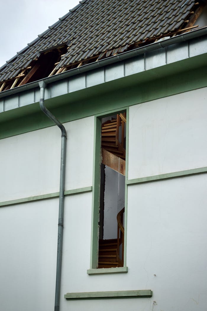 why-choose-us-02 An exterior view of a damaged house showing a broken roof and exposed interior structure.